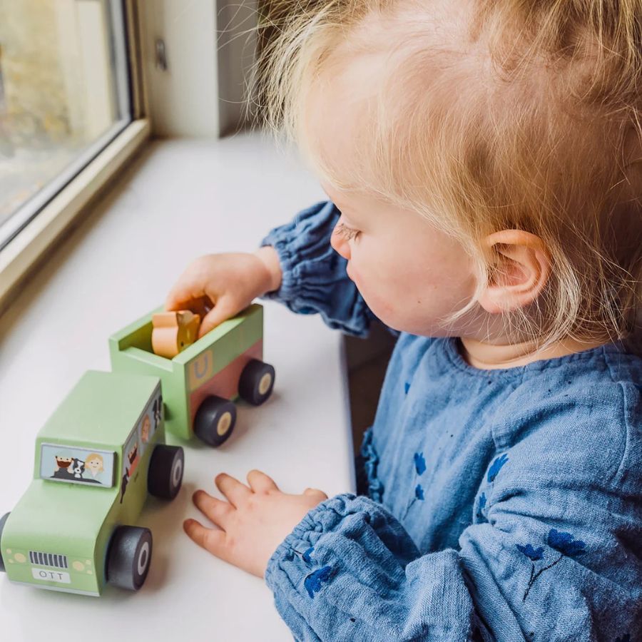 Child playing with wooden car & pony trailer