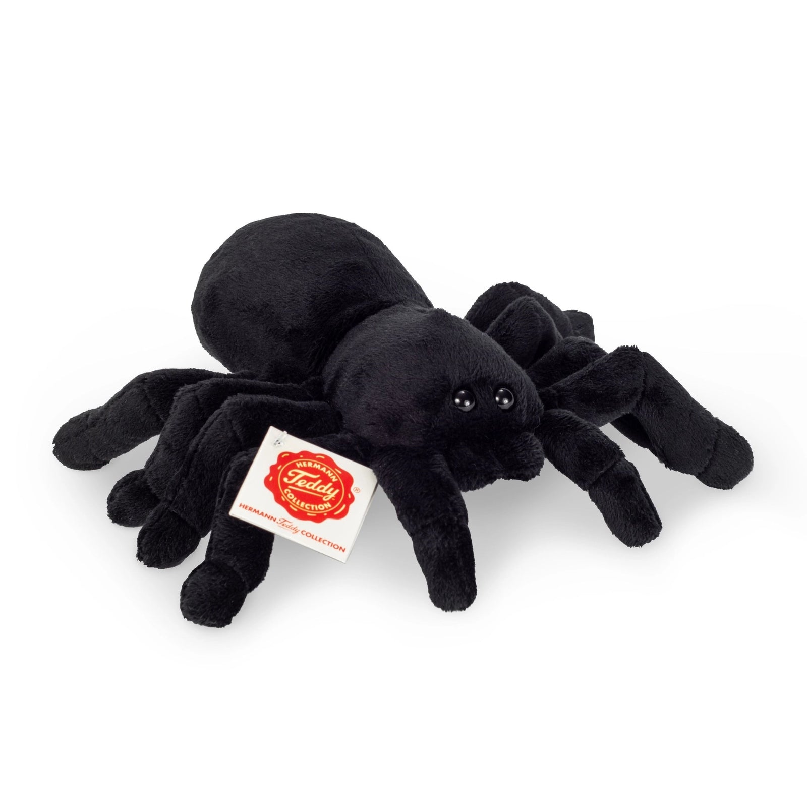 Black plush spider toy with a visible brand tag on a white background