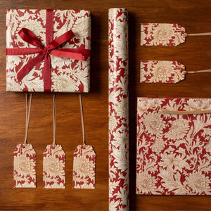 Red and white floral gift wrap with matching ribbons and tags on a wooden surface