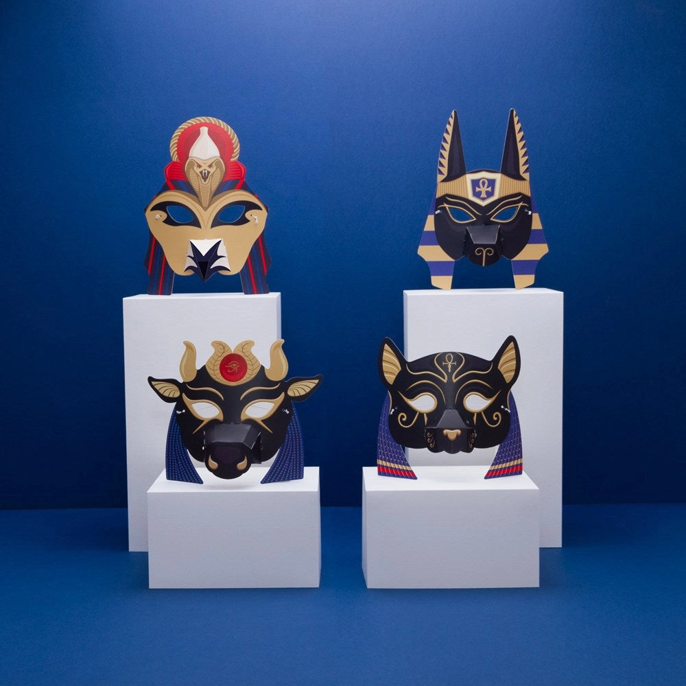 Four Egyptian-style masks on white stands against a blue background