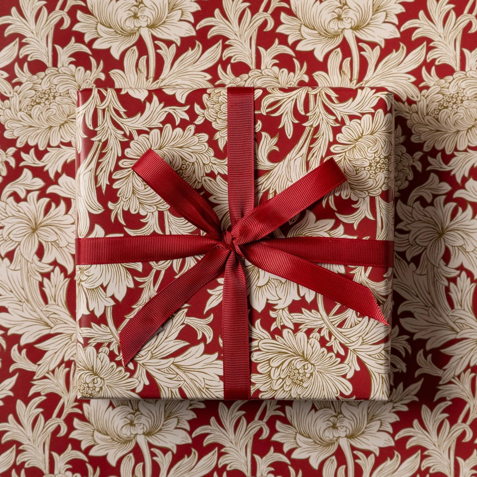 Gift box with red ribbon on a floral patterned background