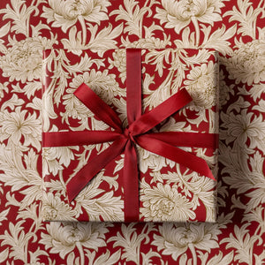 Gift box with red ribbon on a floral patterned background