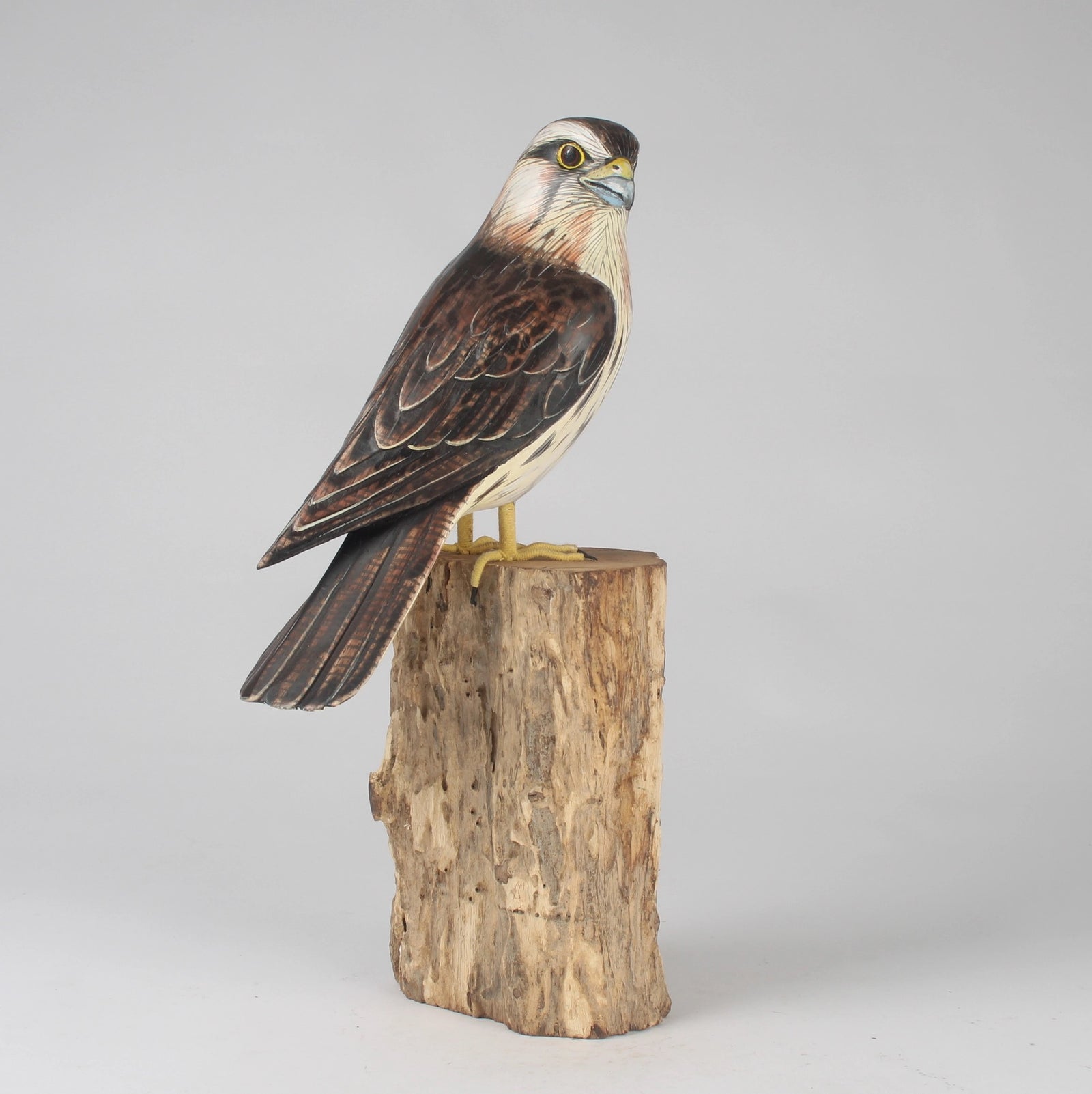 Wooden bird sculpture on a wooden block against a gray background