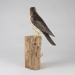 Kestrel  bird sculpture on a natural wood block against a light gray background