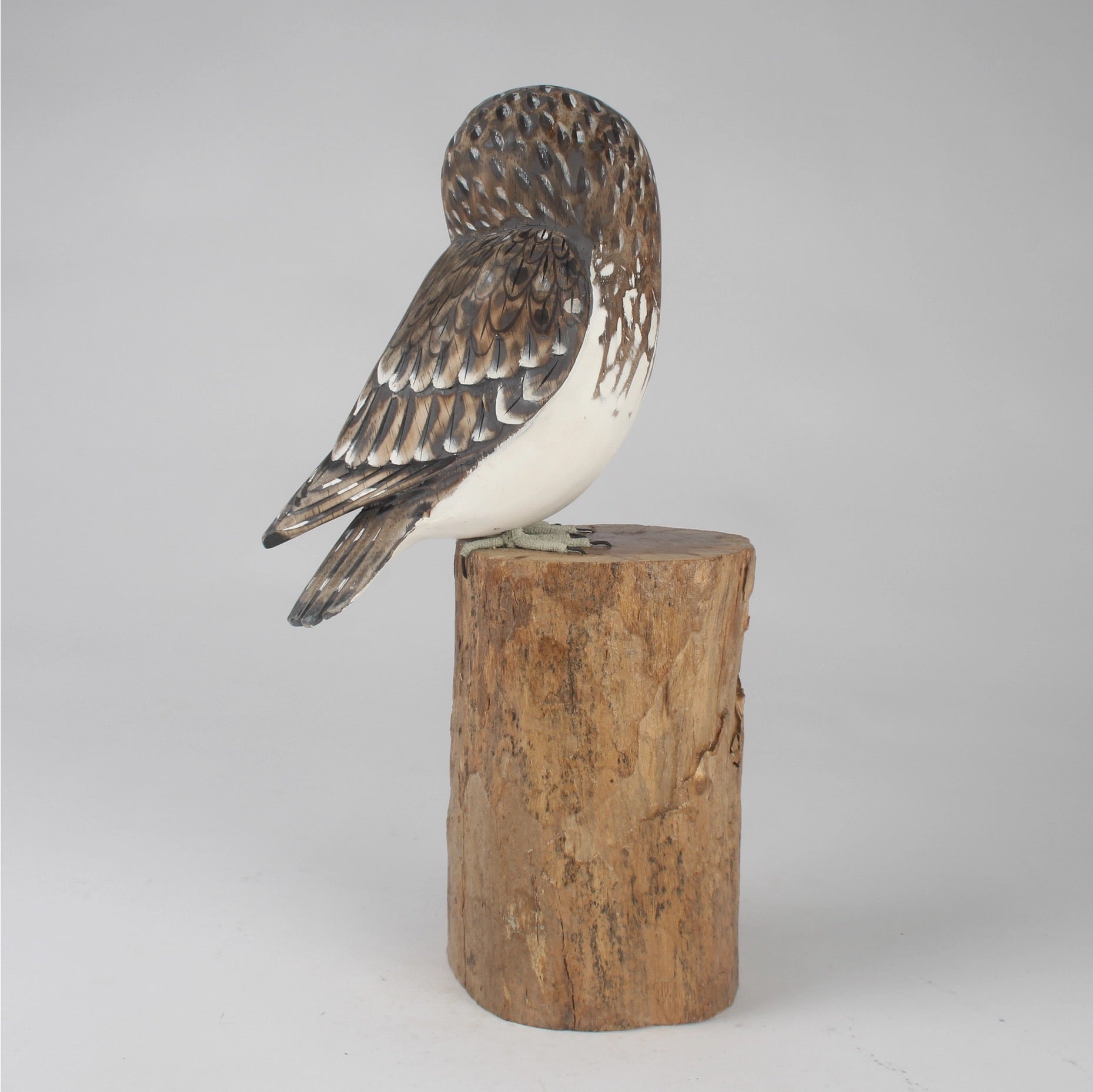 Wooden owl figurine on a cylindrical wooden base against a gray background