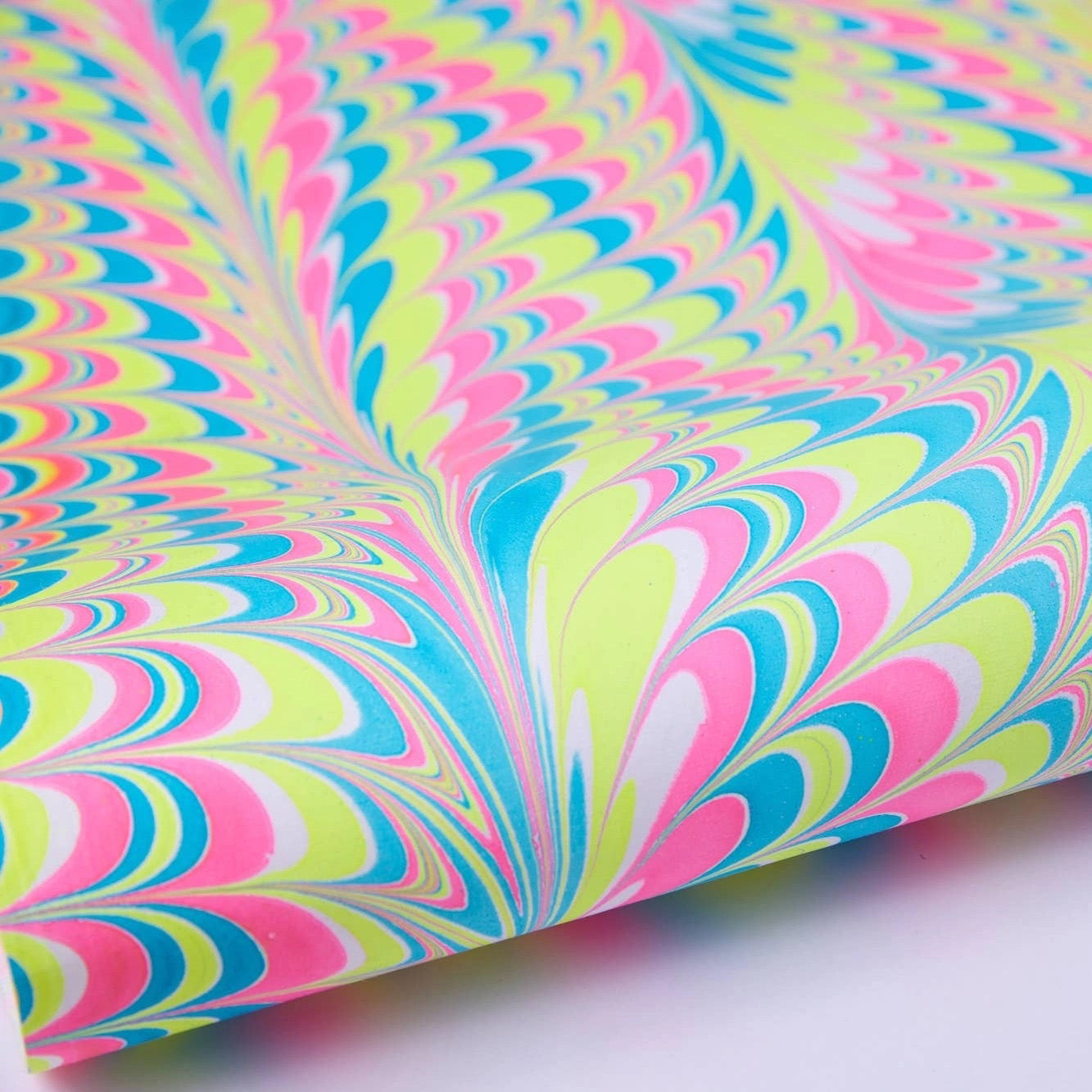 Colourful hand marbled cotton gift wrap with pink, blue, and green patterns on a white background