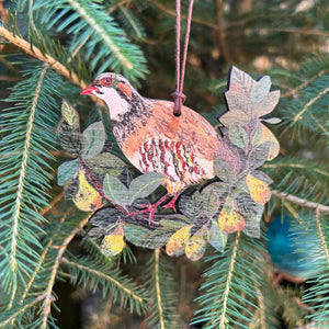 Wooden partridge decoration shown hanging on a fir tree branch